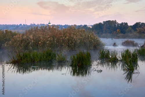 Haze over the river in the early autumn morning. Reeds mist fog and water surface on the river at sunrise