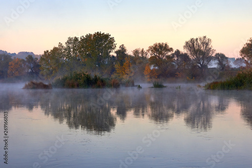 Haze over the river in the early autumn morning. Reeds mist fog and water surface on the river at sunrise