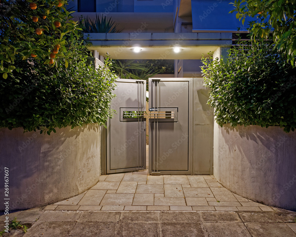 contemporary house entrance metallic grey door late in the evening - obrazy, fototapety, plakaty 
