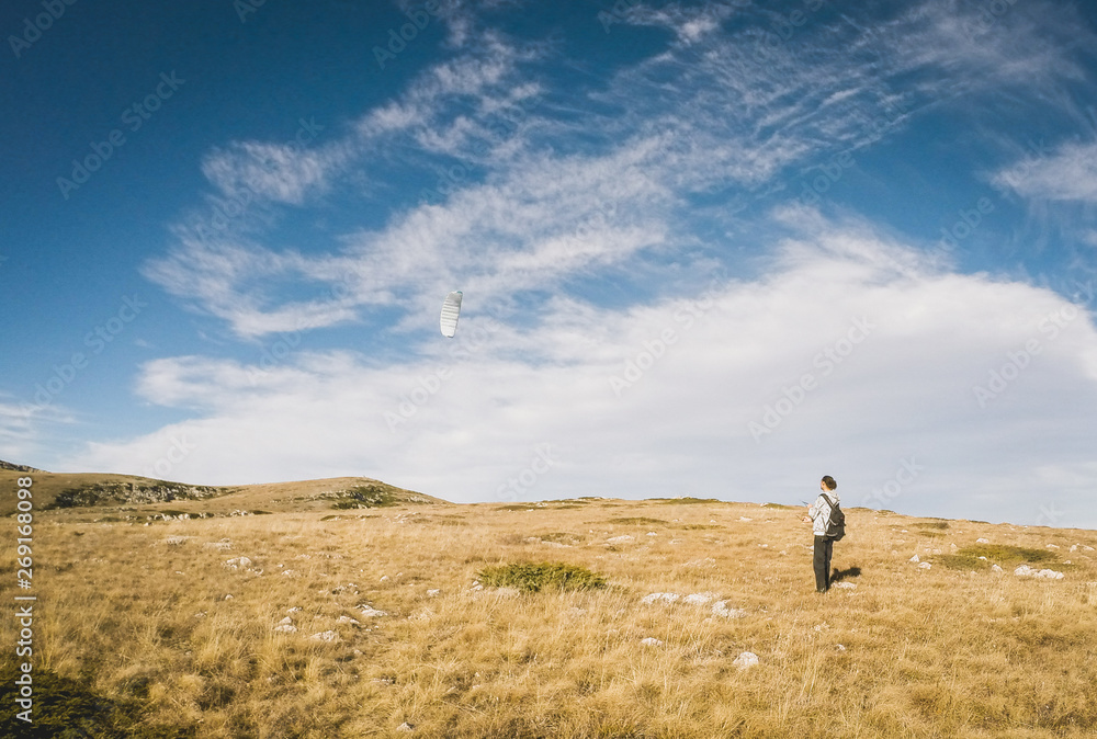 Beautiful summer sunny mountain landscape with a clear blue sky with clouds background. Crimean mountains. young man is running small paraglider. Learning paragliding. Launch a paraglider Beautiful summer sunny mountain landscape with a clear blue sky with clouds background. Crimean mountains. young man is running small paraglider. Learning paragliding. Launch a paraglider