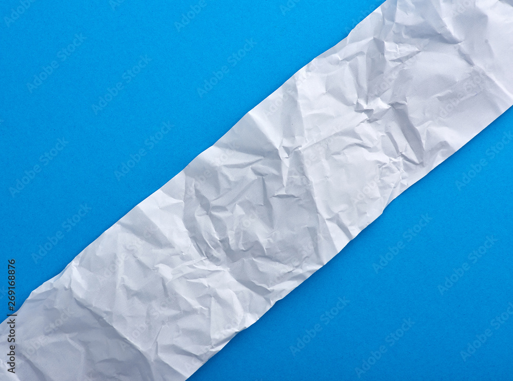Obraz premium strip of crumpled blank white paper on a blue background