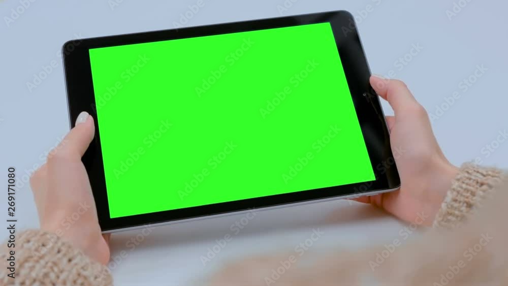Woman sitting at table and looking at black digital tablet computer device with blank green screen in cafe. Technology, chroma key, template, mockup and entertainment concept Woman sitting at table and looking at black digital tablet computer device with blank green screen in cafe. Technology, chroma key, template, mockup and entertainment concept