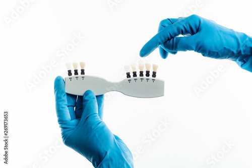 Hands in blue gloves holding dental color palette isolated on white background photo