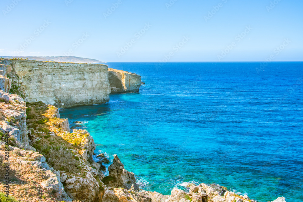 Cliff on the picturesque coast of the Mediterranean Sea with turquoise water.