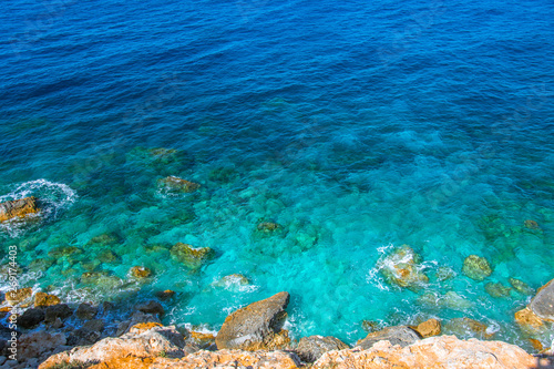 View of the stones of the coast and the heavenly turquoise water in the sea.