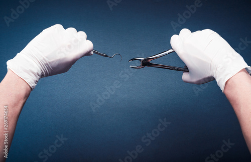 Hands in gloves holding surgery dental tools on dark blue background photo