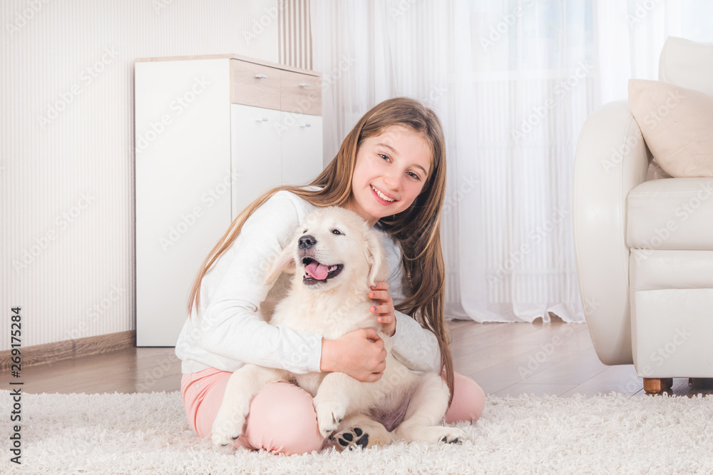Teenage girl lying with cute fluffy retriever puppy on carpet