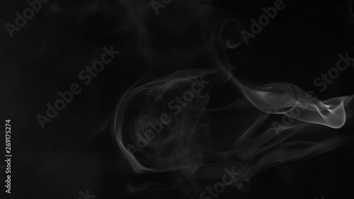 slow motion puffs of white smoke moving from right to left on a black background