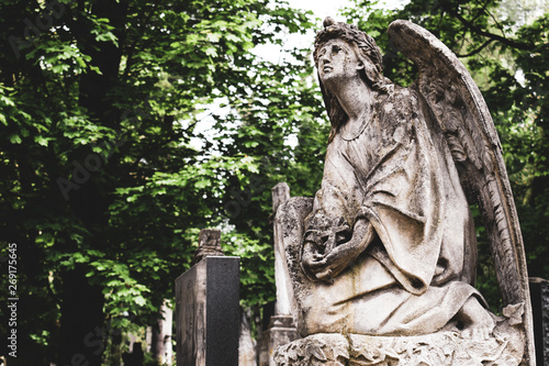 Obsolete old stature of angel with cross on burial on cemetery in Lychakiv Cemetery, Lviv