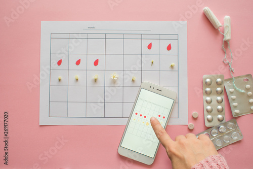 Menstrual cycle. Calendar for the month with marks and a mobile application on the smartphone screen. photo