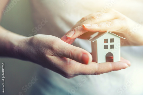 Female woman hands holding small miniature white toy house. Mortgage property insurance dream moving home and real estate concept