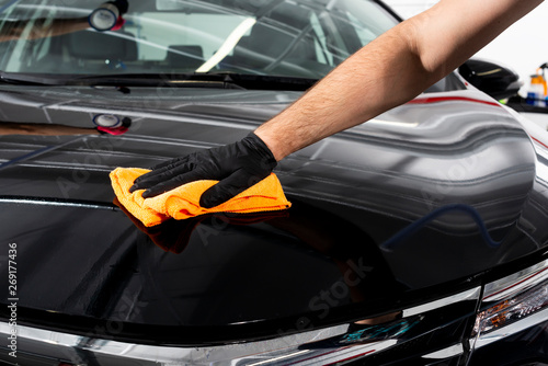 A man cleaning car with microfiber cloth. Car detailing or valeting concept. Selective focus. Car detailing. Cleaning with sponge. Worker cleaning. Car wash concept solution to clean