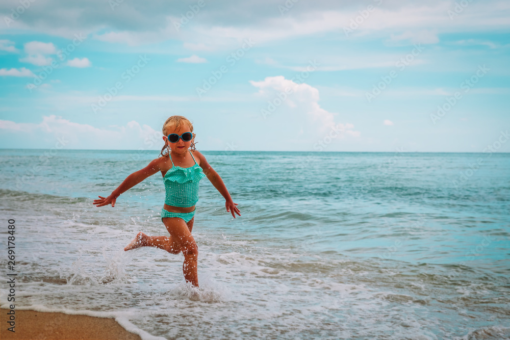 happy little girl run play with waves on beach happy little girl run play with waves on beach