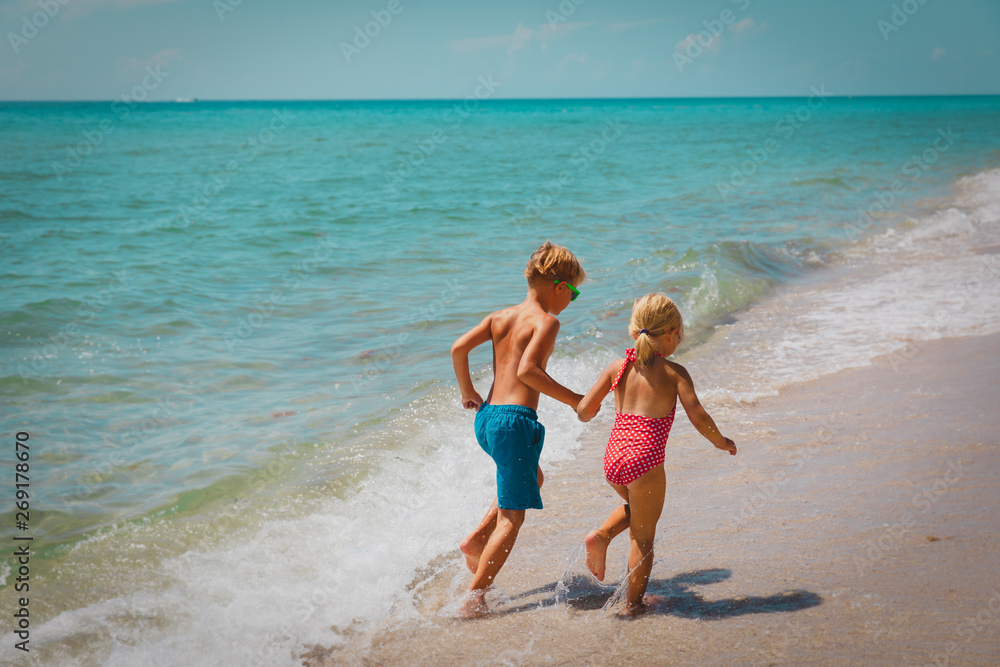 little girl and boy run play with waves on beach little girl and boy run play with waves on beach