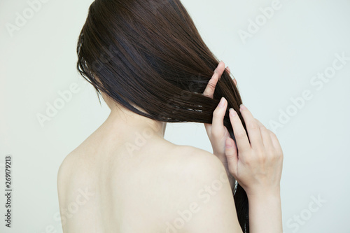 自分の髪の毛を触る女性の後ろ姿