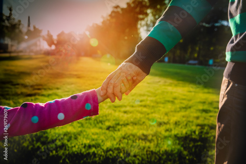 father and little daughter holding hands at sunset, parenting