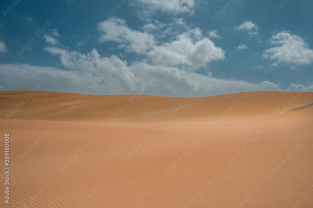 sand dunes in the desert with clouds and a blue sky