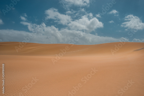 sand dunes in the desert with clouds and a blue sky