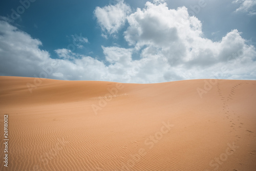 sand dunes in the desert with clouds and a blue sky