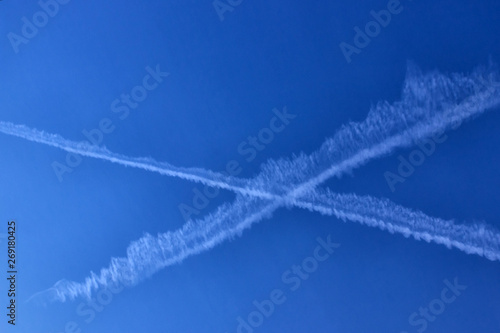 Trace of the plane in the blue sky. Sunny day. Greece. Concept- travel, vacation,  geoengineering and chemtrails.
