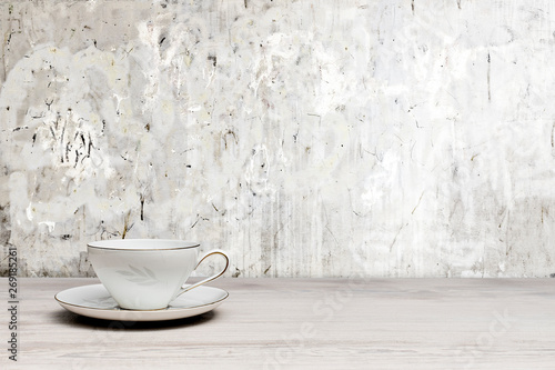 Vintage teacup on a white wooden table, textured wall