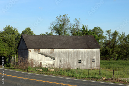 Old weathered wooden barn on side of country road