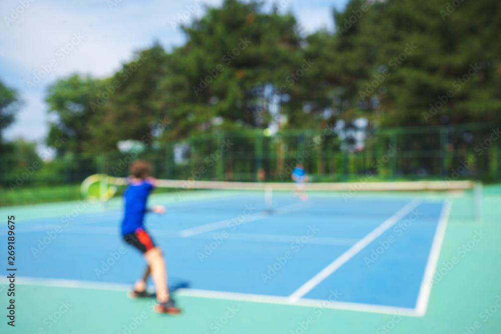 Teenager boy playing tennis on court. Sport summer concept. Blurred background.