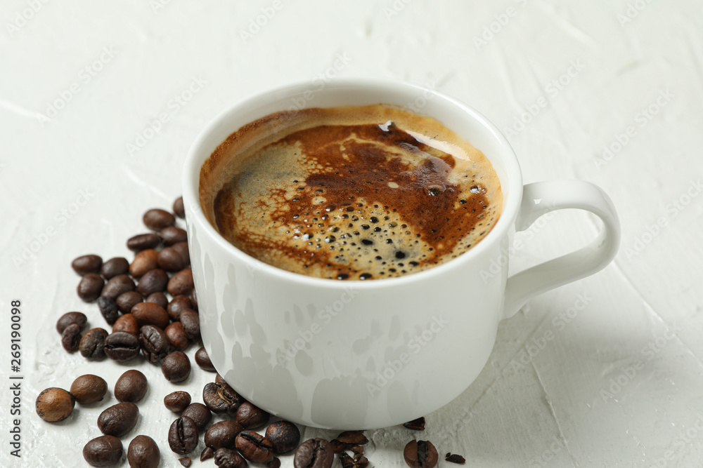 Cup of coffee with frothy foam and coffee beans on white background, closeup and space for text. Coffee time accessories Cup of coffee with frothy foam and coffee beans on white background, closeup and space for text. Coffee time accessories