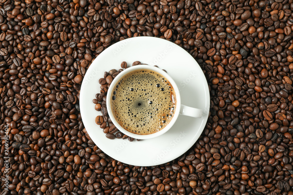 Cup of coffee with frothy foam on beans background, top view and space for text. Coffee time accessories Cup of coffee with frothy foam on beans background, top view and space for text. Coffee time accessories