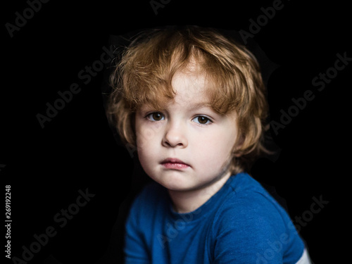 portrait of a little serious sad child on a dark background