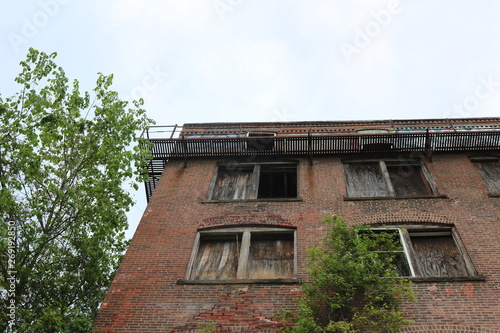 Old abandoned condemned brick building with broken boarded up glass windows