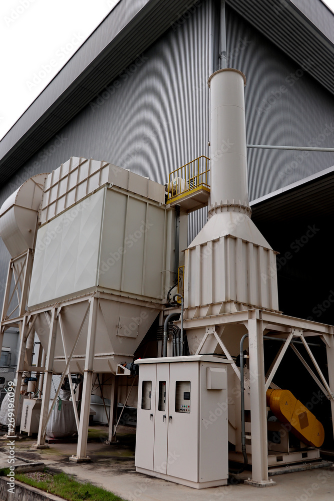 Air pollution control equipment as dust filter collection and chimney stack  locates out of industrial building. Photos | Adobe Stock