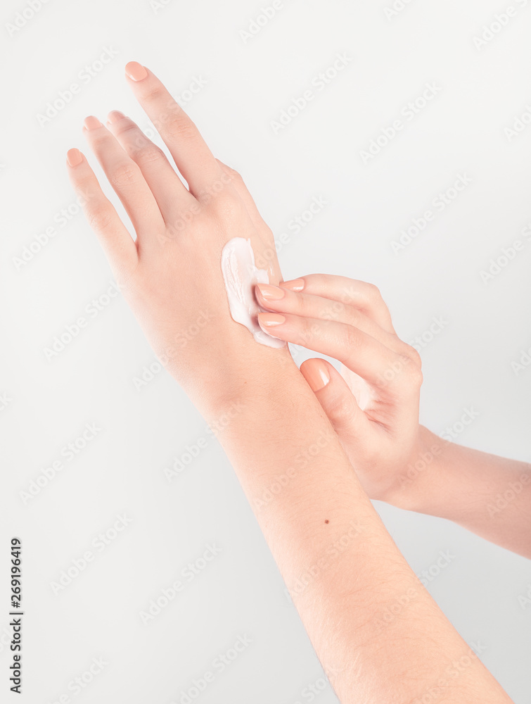 Spa treatment. Close Up of female hands applying hand cream. Woman holding cream tube and applying moisturizer cream on her beautiful hands for clean and soft skin. Spa treatment. Close Up of female hands applying hand cream. Woman holding cream tube and applying moisturizer cream on her beautiful hands for clean and soft skin.