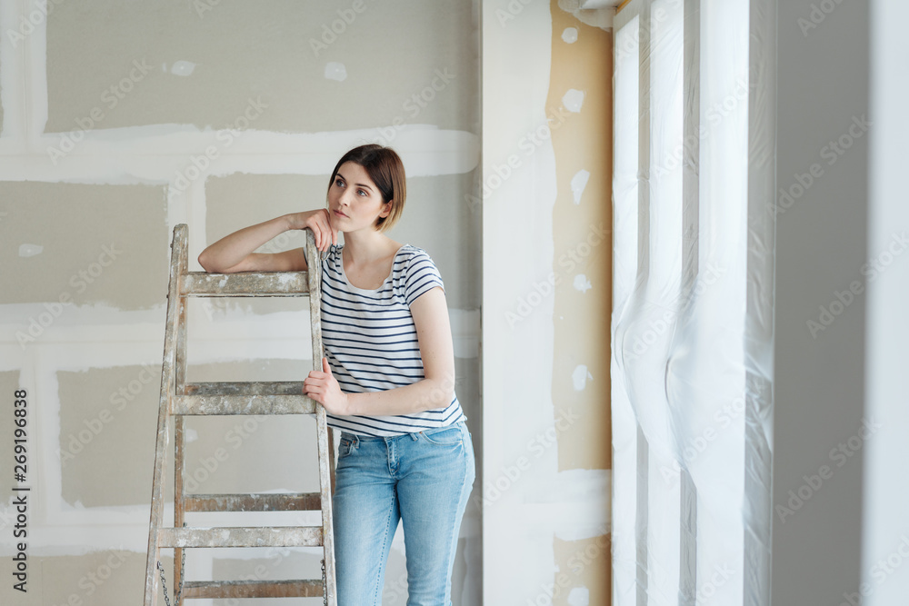 Thoughtful woman eyeing up ongoing renovations Thoughtful woman eyeing up ongoing renovations