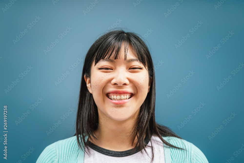 Portrait of young Asian girl smiling at camera - Happy Chinese woman having fun posing against blue background - Teen, trendy, millennial generation and youth people lifestyle Portrait of young Asian girl smiling at camera - Happy Chinese woman having fun posing against blue background - Teen, trendy, millennial generation and youth people lifestyle