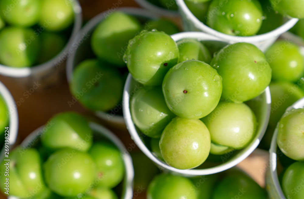 Top view of green plums or greengage in paper cup on sale in the street in Turkey, popular spring fruits with a very sharp sour taste in Iran Top view of green plums or greengage in paper cup on sale in the street in Turkey, popular spring fruits with a very sharp sour taste in Iran