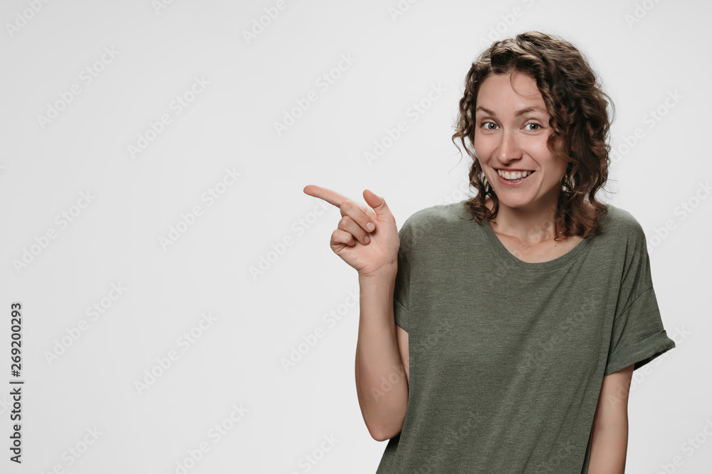 Portrait of happy young woman indicates with index finger at blank copy space Portrait of happy young woman indicates with index finger at blank copy space