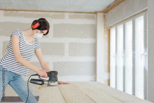 Foto Young woman using an orbital sander on wood