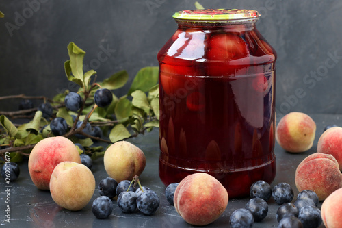 Compote with peaches and berries of blackthorn in jar on a dark background, harvest for the winter