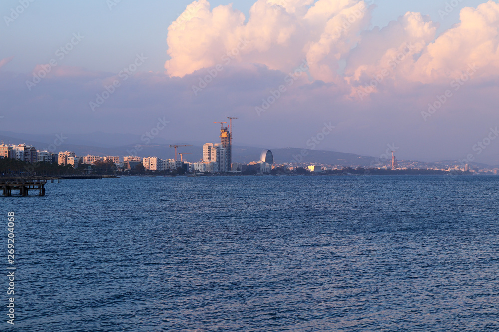 Beautiful Coastline of Limassol at sunset. Perfect coast of Lemesos with many high-rise buildings. Cloudy sky with red and pink colour from setting sun. Second biggest city in Cyprus