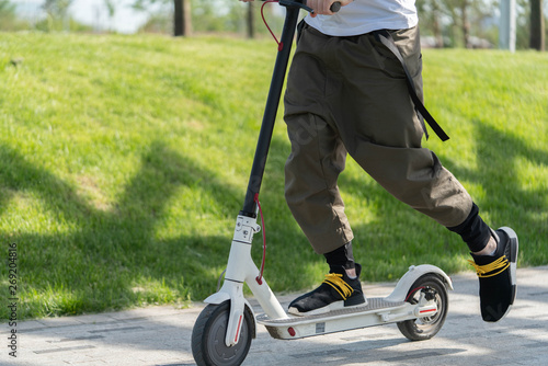 Close up of man riding electric kick scooter at beautiful park landscape.