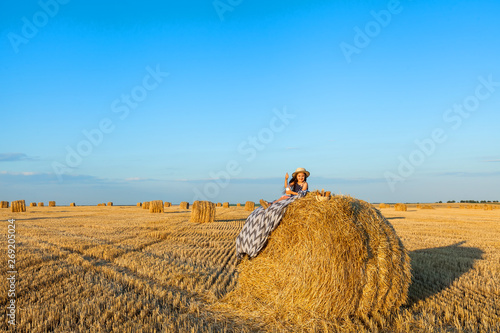 Cute little child in rye field with hay stacks on sunset.
