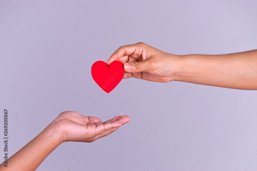 Woman hand gives a red heart to a boy hand for blood donation concept,World blood donor day. Copy space for advertisers. Woman hand gives a red heart to a boy hand for blood donation concept,World blood donor day. Copy space for advertisers.