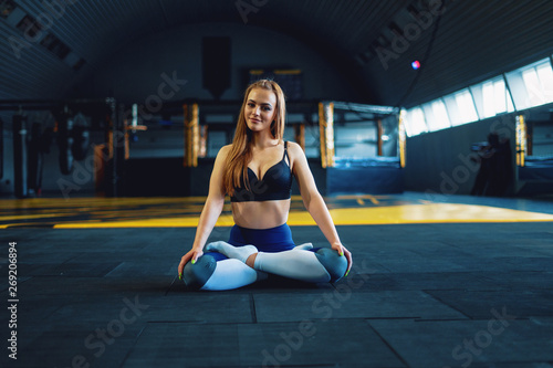 Stretching gymnast girl doing yoga exersizes. View of attractive young woman doing lotus pose
