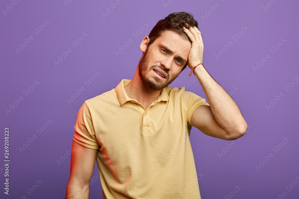 tired sad man with hand on his forehead looking at the camera. close up portrait. tiredness, exhausted man in yellow T-shirt cannot solve his problems tired sad man with hand on his forehead looking at the camera. close up portrait. tiredness, exhausted man in yellow T-shirt cannot solve his problems