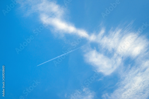 Blue sky with white clouds and jet trail.