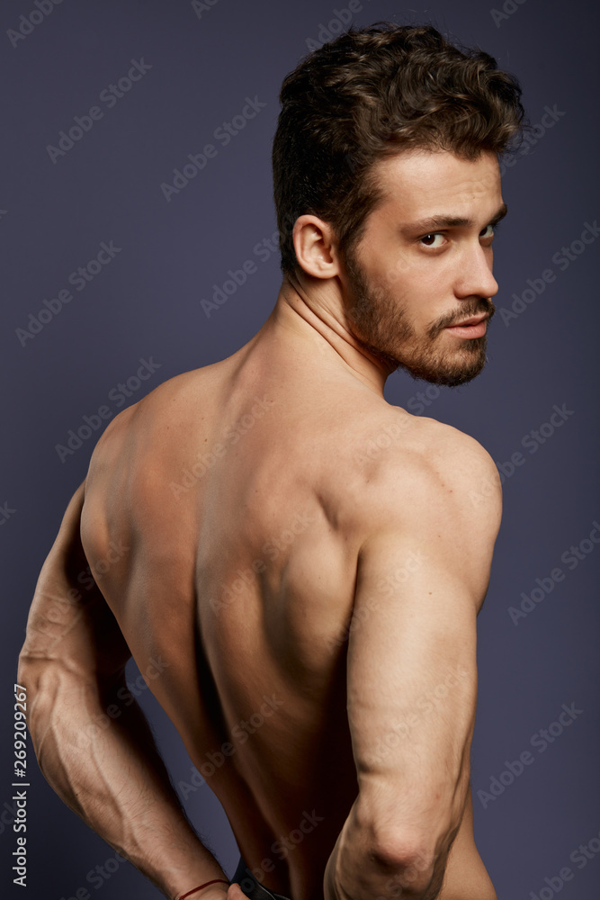 Strong handsome man showing back muscles, triceps, latissimus. close up photo. isolated black