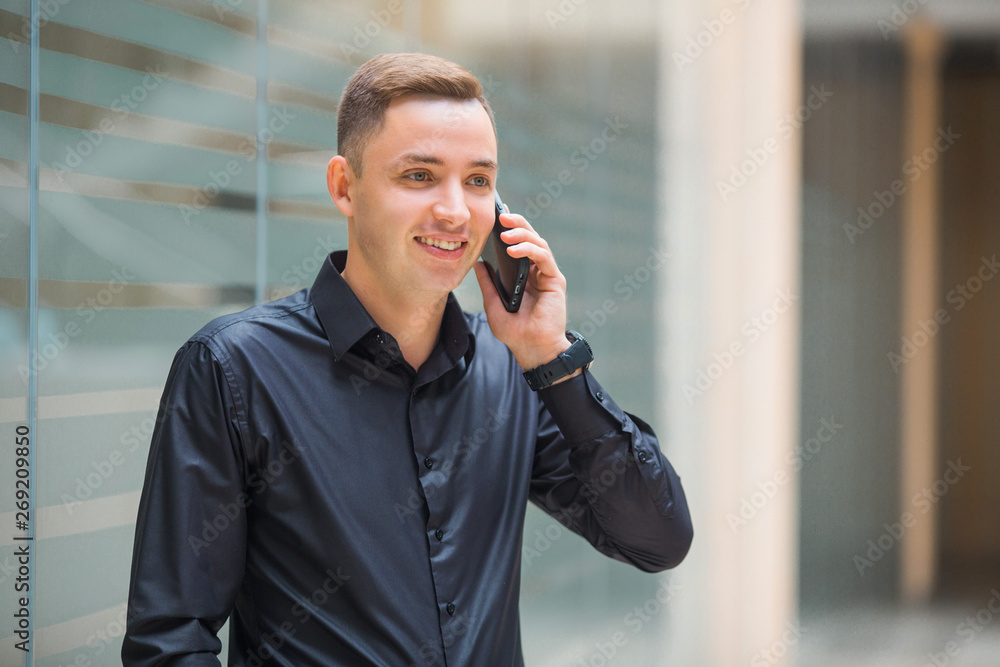 handsome young man in black shirt indoors talking on the phone handsome young man in black shirt indoors talking on the phone