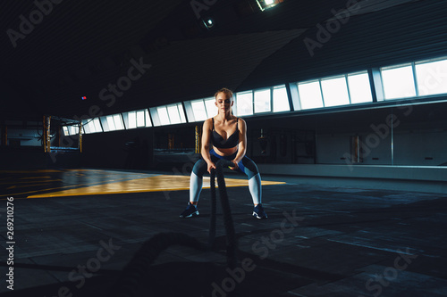 Full length wide angle shot of a young woman working out with battle ropes. Copyspace background with athletics healthy composition. Crossfit and fitness