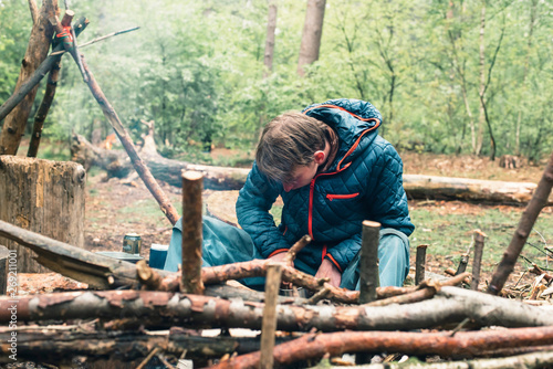 Young man preparing campfire in forest.